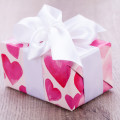 Pretty Valentines gift with hearts on the giftwrap on a big white ornamental bow on top, closeup high angle view of a gift for a loved one or sweetheart
